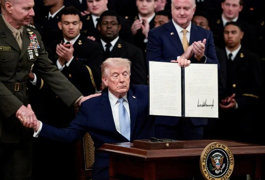 US President Donald Trump holds an executive order to reserve the broadcast on the second Saturday in December exclusively for the Army-Navy football game, during a presentation of the Commander-in-Chief's trophy to the US Navy Midshipmen football team of the United States Naval Academy, at the White House in Washington, DC, US, 20 March 2026.