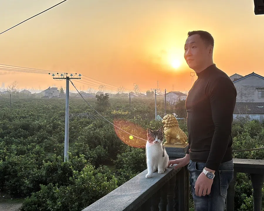 Post-90s bachelor Yi Chunlei with his cat on his balcony.