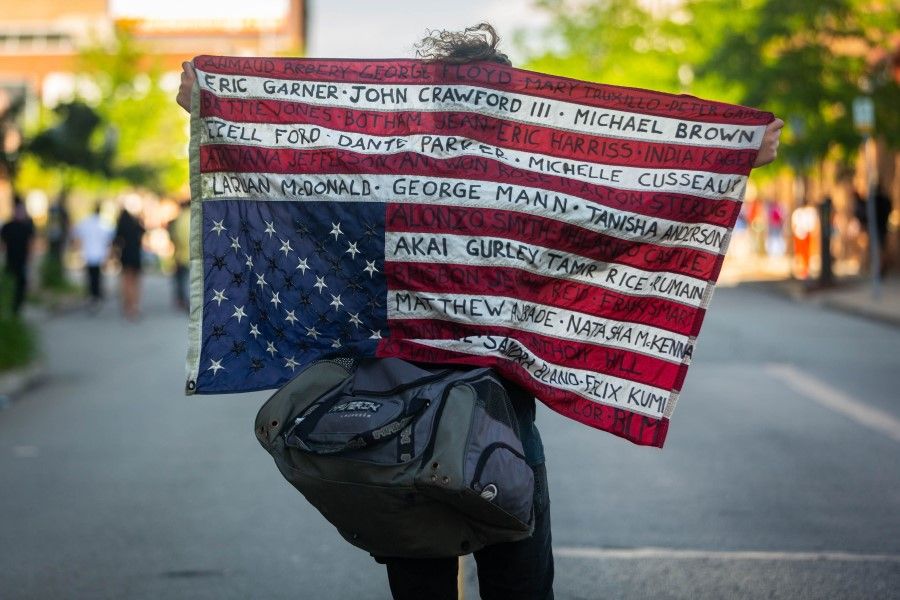 A protester holds up an upside-down US flag with names of victims during a demonstration against racism and police brutality in Pittsburgh, Pennsylvania, 6 June 2020. (Maranie R. Staab/AFP)