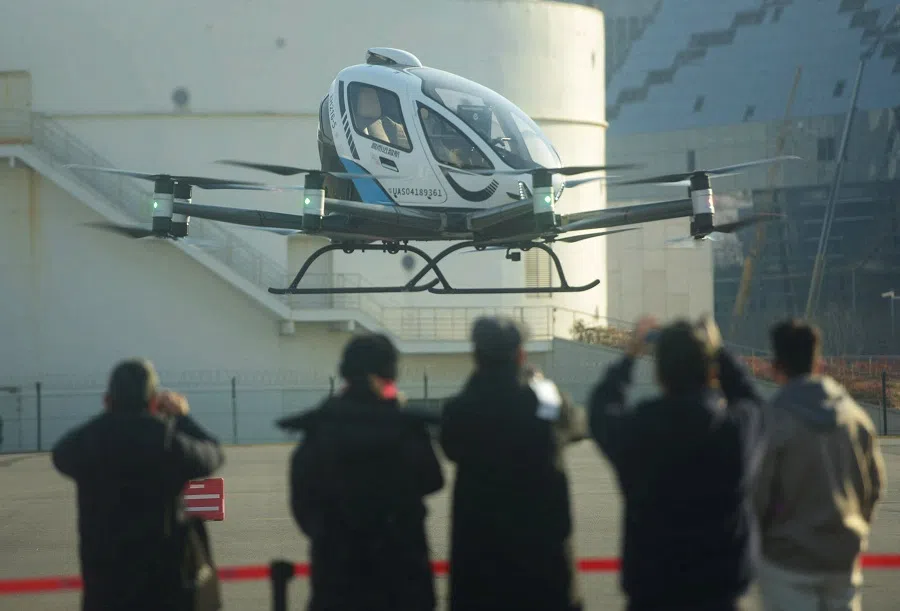 This photo taken on 16 January 2025 shows people watching an EH216-S, a two passenger electric vertical take-off and landing (eVTOL) multicopter production model made by Guangzhou EHang Intelligent Technology Co. Ltd. (EHang), during its first public flight in Shanghai, at Longhua Heliport, China.