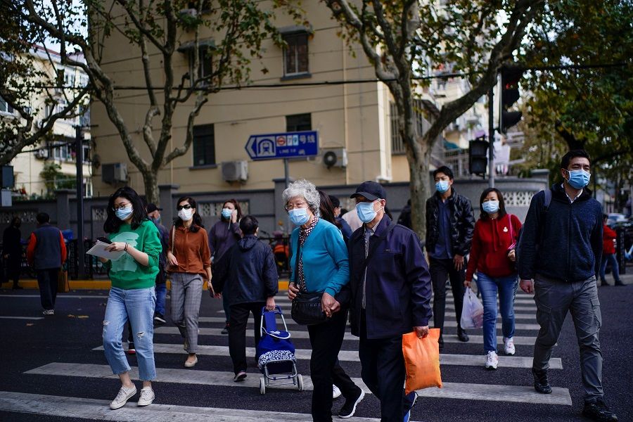 People wearing face masks are seen on a street amid the global outbreak of the Covid-19 coronavirus in Shanghai, China, 18 November 2020. (Aly Song/Reuters)