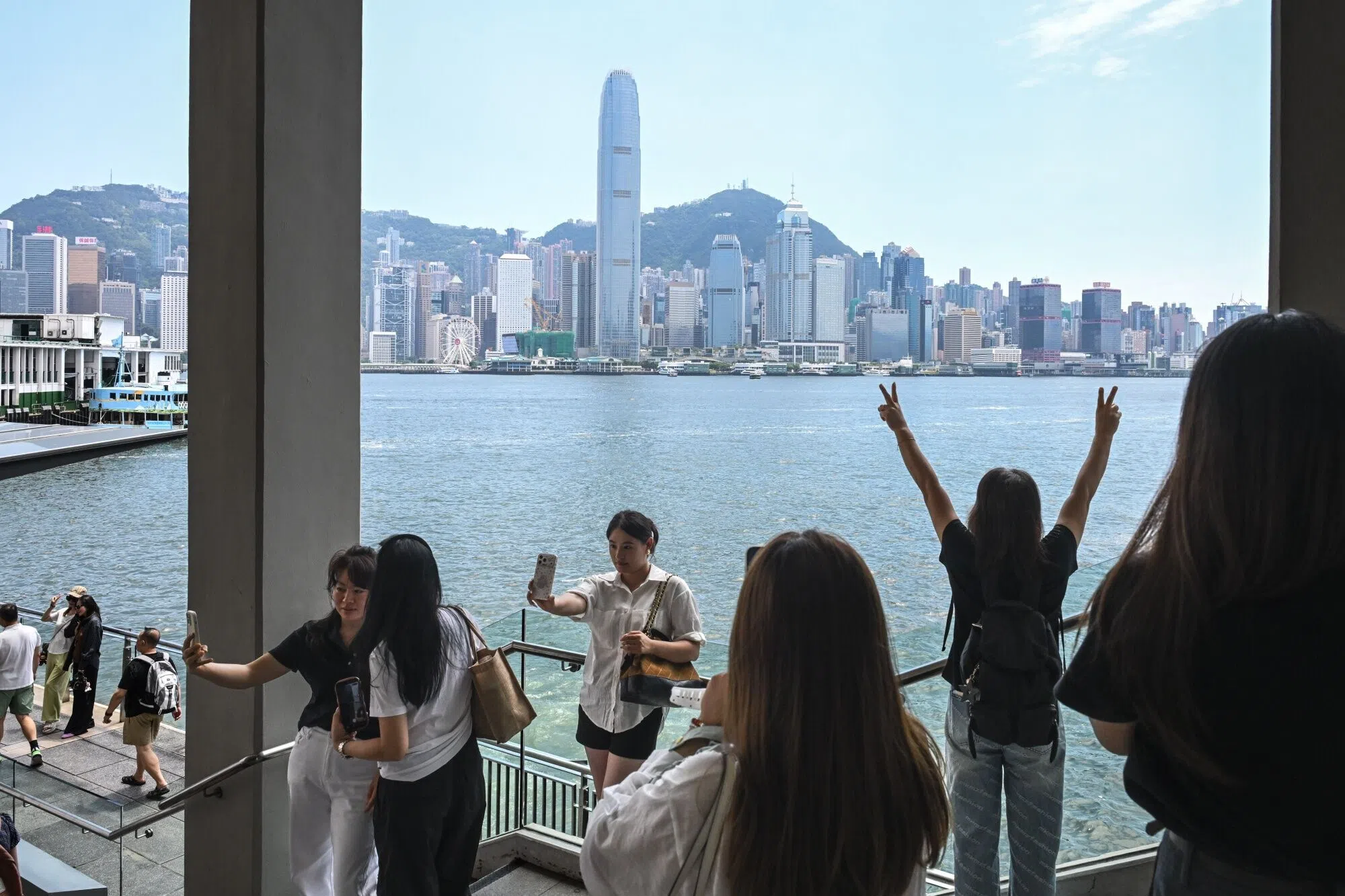 Visitors take photographs in the Tsim Sha Tsui area in Hong Kong, China, on 11 August 2026.