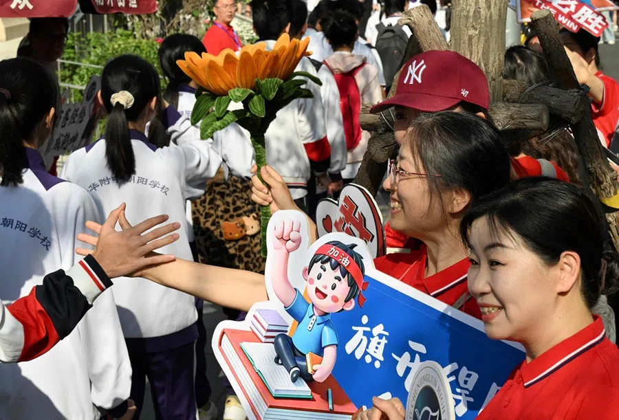 School staff welcome students as they enter a school during China’s National College Entrance Examination (NCEE), known as “gaokao”, outside a high school in Beijing, China, on 7 June 2025. (Adek Berry/AFP)