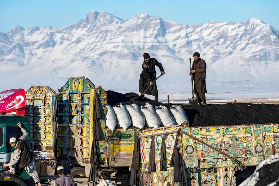 Afghan labourers shovel coal onto a truck bound for Pakistan, at a coal yard on the outskirts of Kabul on 6 January 2025. (Wakil Kohsar/AFP)
