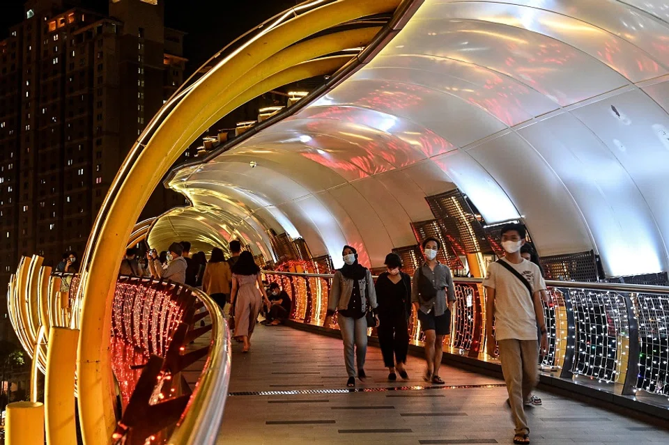 People walk along a bridge that connects two shopping malls in Jakarta on 14 February 2021. (Adek Berry/AFP)