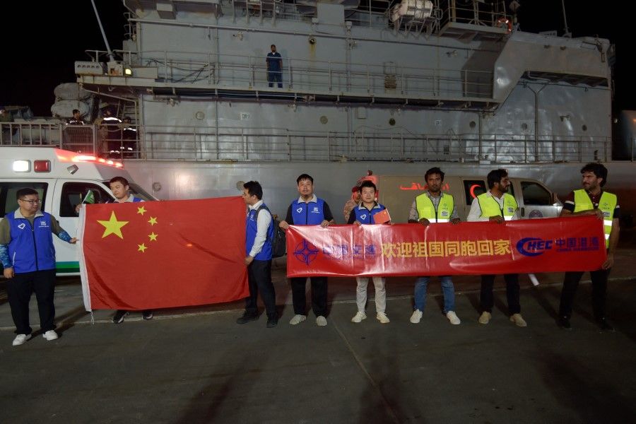 Chinese citizens evacuated from Sudan deploy a large national flag and upon their arrival at King Faisal navy base in Jeddah on 26 April 2023. (Amer Hilabi/AFP)