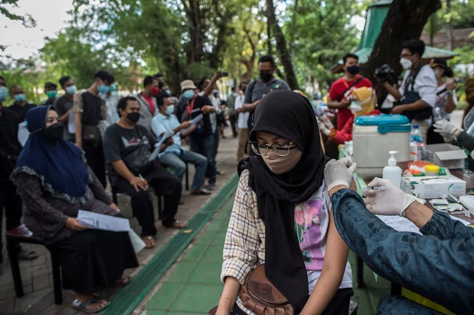 A health worker inoculates a woman with a dose of the Sinovac Covid-19 vaccine during a mass vaccination at a zoo in Surabaya, Indonesia, on 13 September 2021. (Juni Kriswanto/AFP)