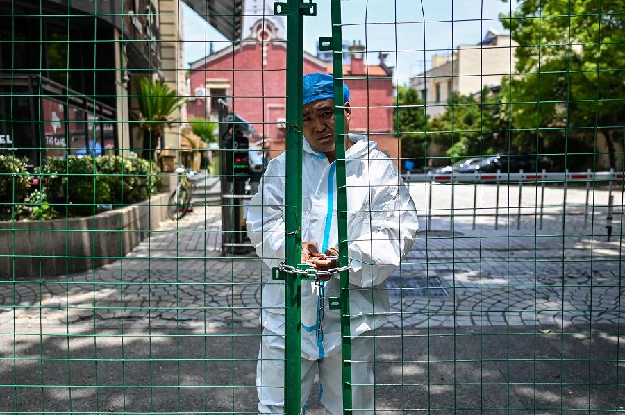 A worker padlocks fencing securing a residential area under Covid-19 lockdown in the Xuhui district of Shanghai, China, on 8 June 2022. (Hector Retamal/AFP)