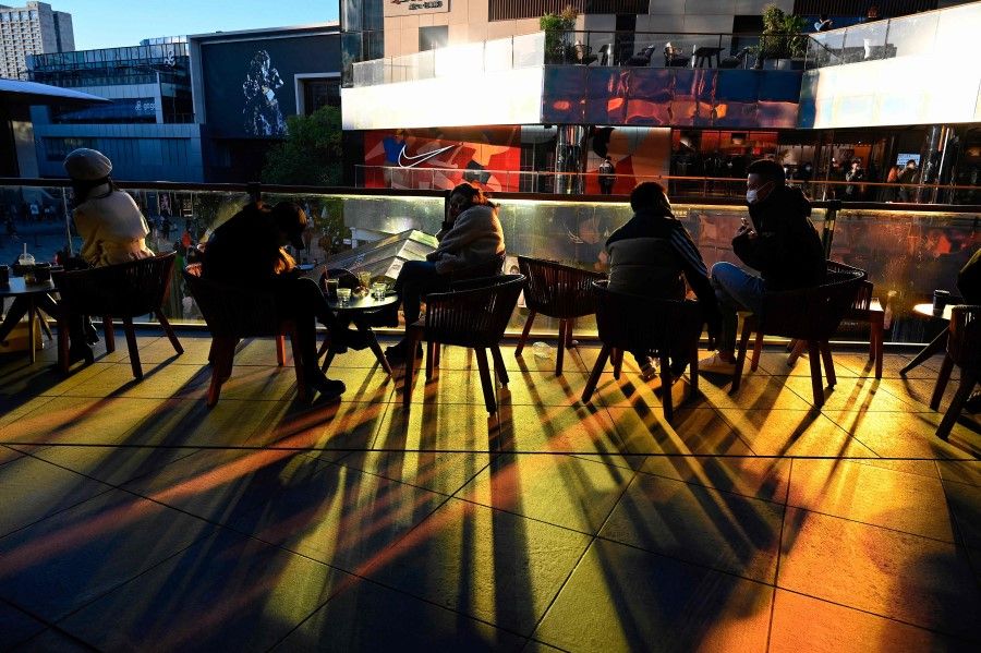 People sit on the balcony of a shopping mall in Beijing on October 16, 2021. (Photo by Jade Gao / AFP)
