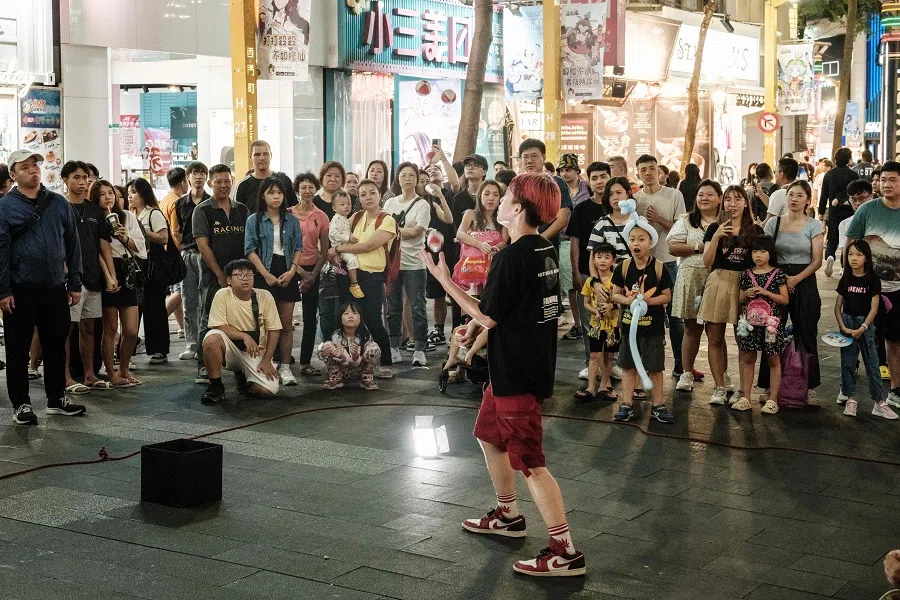 People watch a street performer on a street in Taipei on 26 May 2024.