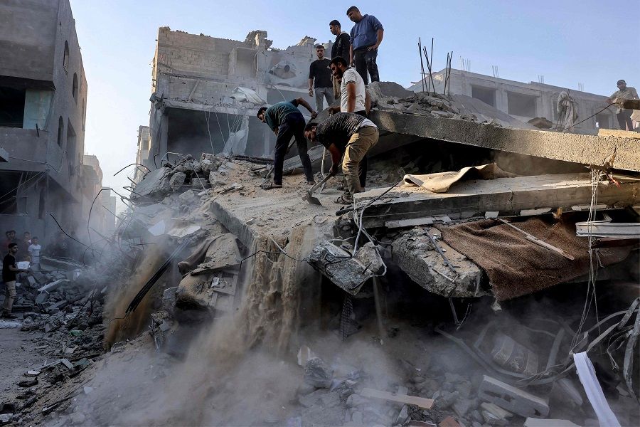 People dig and search through the rubble of a destroyed building following Israeli bombardment in Rafah in the southern Gaza Strip on 19 October 2023. (Mohammed Abed/AFP)