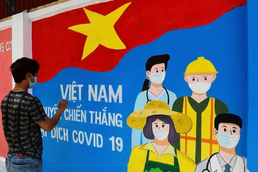 In this file photo, a street artist paints a mural depicting Covid-19 coronavirus frontline workers along a street in Hanoi on 15 June 2021. (Nhac Nguyen/AFP)