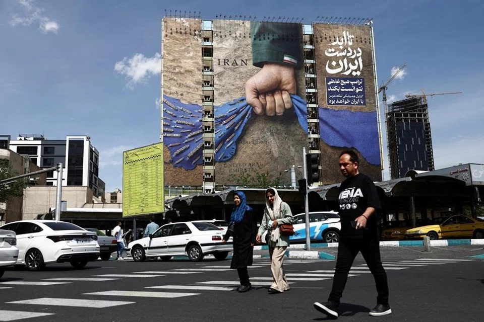 People walk past a billboard with a graphic design about the Strait of Hormuz on a building, in Tehran, Iran, 27 April 2026. (Majid Asgaripour/West Asia News Agency via Reuters)