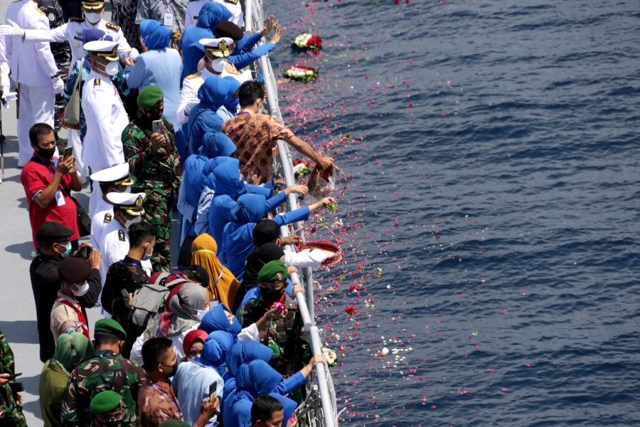 Families and colleagues of the sunken KRI Nanggala-402 submarine's crew members throw flowers and petals during a tribute on the deck of Indonesian Navy's KRI Dr. Soeharso, in waters off the island of Bali, Indonesia, 30 April 2021. (Antara Foto/Budi Candra Setya/via Reuters)
