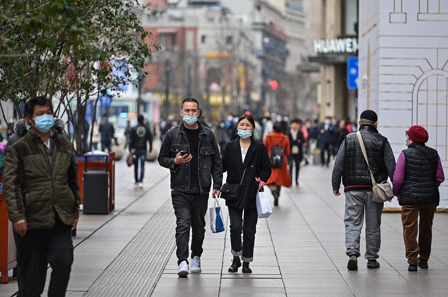 In this photo taken on 5 March 2021, a couple walks on a shopping street in Shanghai, China. (Hector Retamal/AFP)