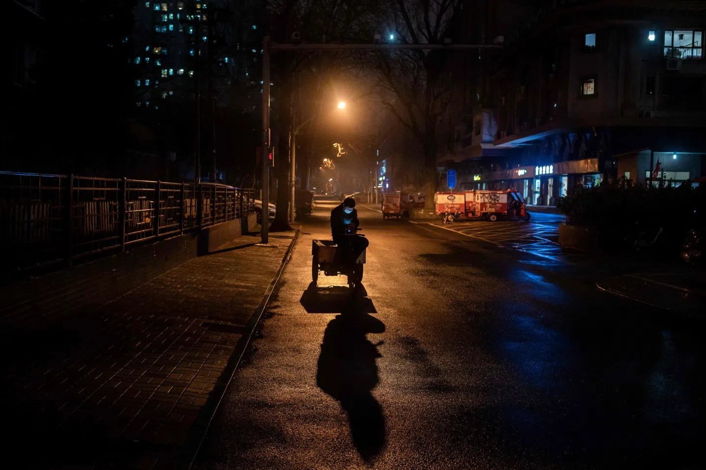 A man wearing a face mask as a preventive measure against the Covid-19 coronavirus uses his phone as he sits on an electric vehicle in Beijing on 8 March 2020.(Nicolas Asfouri/AFP)