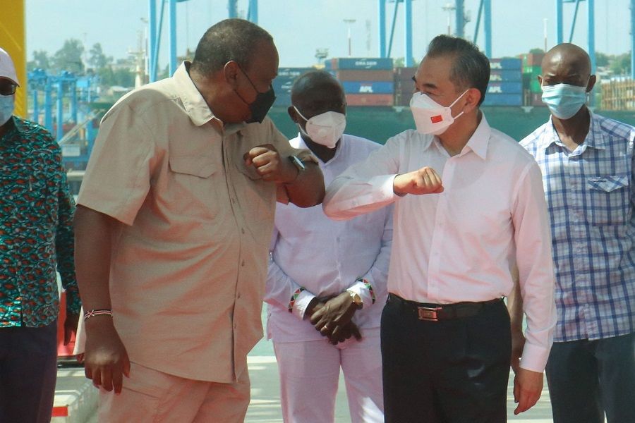 Kenyan President Uhuru Kenyatta (left) greets China's Foreign Minister Wang Yi (right) during an inspection tour of the New Kipevu Oil Terminal at Mombasa Port in Mombasa, Kenya, on 6 January 2022. (AFP)