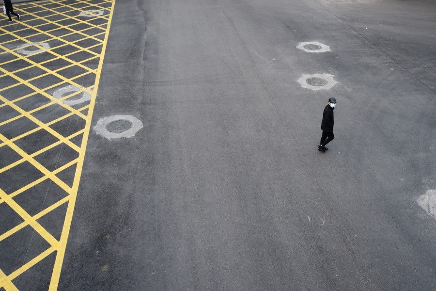 A man wearing a face mask crosses a road in Wuhan. China has not handled the Covid-19 epidemic well, and its shortcomings are showing. (Reuters)