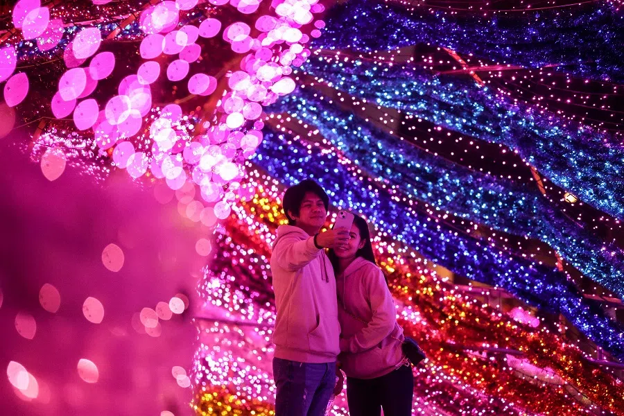 A couple takes a selfie at a Christmas light tunnel during the 2024 New Taipei Christmasland in New Taipei City, Taiwan on 24 December 2024. (I-Hwa Cheng/AFP)
