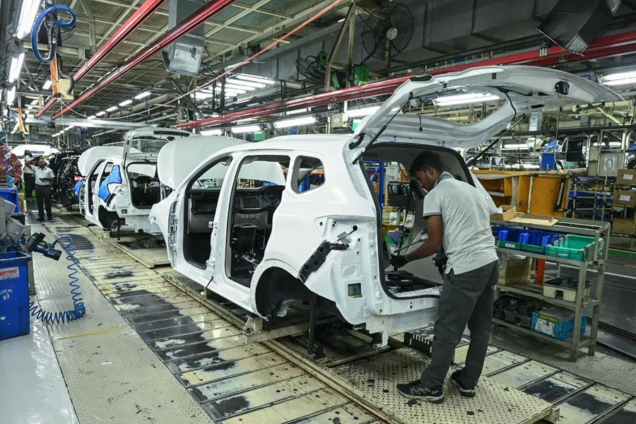 An employee works in a car assembly line at the joint manufacturing facility of Renault Nissan Automotive India, in Oragadam, an industrial suburb of Chennai on 27 March 2024. (AFP)