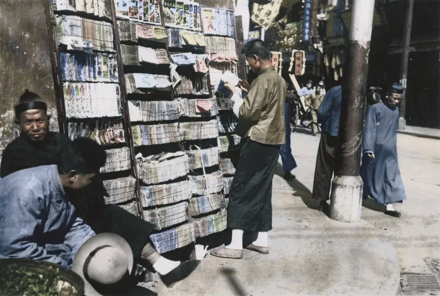 A reader browses at a book stall along the street during the days of the Republic. Traditional street stalls selling books stood firmly amid Shanghai's urban noise of cars, trams and rickshaws.