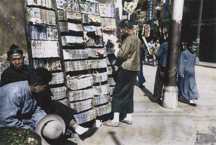 A reader browses at a book stall along the street during the days of the Republic. Traditional street stalls selling books stood firmly amid Shanghai's urban noise of cars, trams and rickshaws.