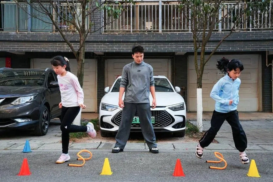 Part-time trainer Hu Yutao leads two students in exercise on 11 March 2026 in Kunming, Yunnan province.