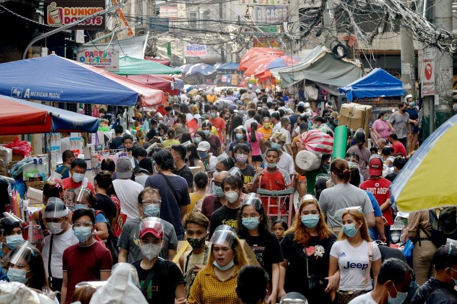 People wearing face masks and face shields as preventive measure against Covid-19 walk along a street market in Manila, Philippines, 14 December 2020. (Lisa Marie David/REUTERS)
