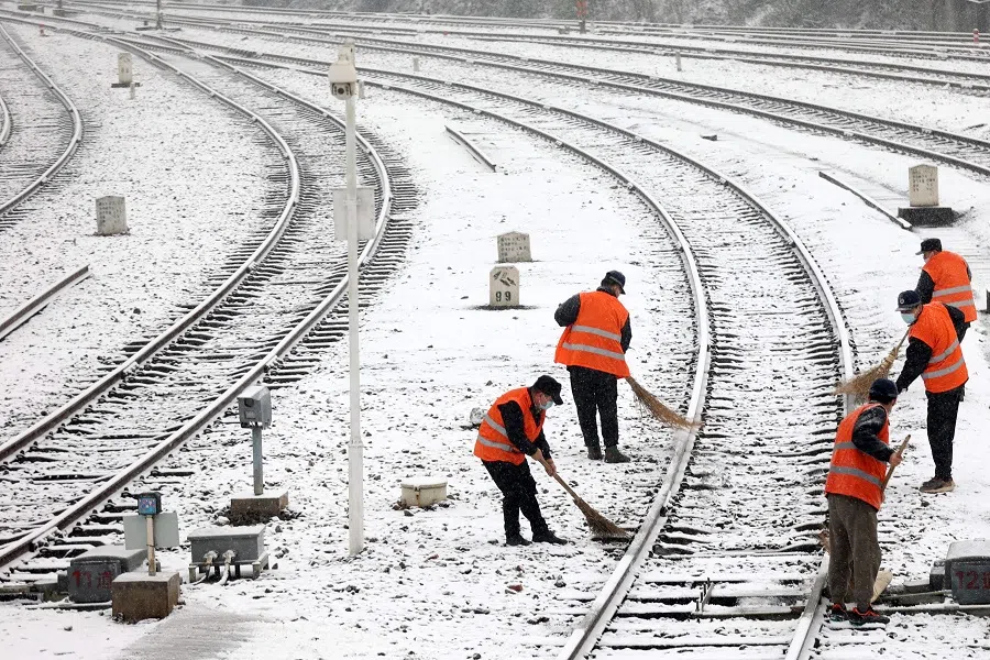 This photo taken on 15 January 2023 shows railway workers clearing snow from a railroad track during snowfall in Jiujiang, Jiangxi province, China. (AFP)