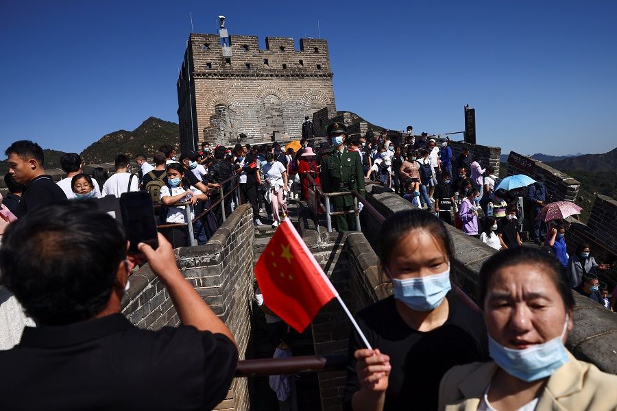 Paramilitary police officers keep watch as people climb the Great Wall in Beijing, China, 1 October 2021. (Thomas Peter/Reuters)