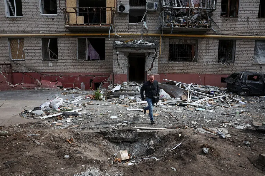 A person runs out of an apartment block to avoid falling debris from a building hit during a Russian drone strike in a residential area, amid Russia’s attack on Ukraine, in Dnipro, Ukraine, on 29 March 2025.