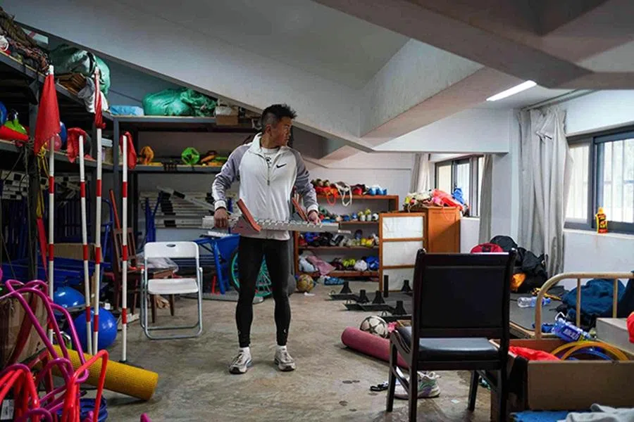House-call personal trainer Li Chengcheng carries his own starting blocks in an equipment room next to his alma mater’s track.