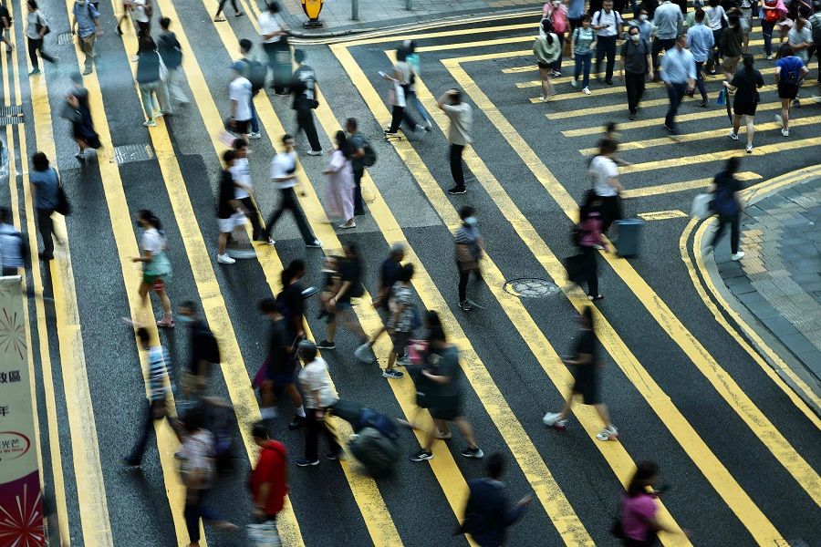 People cross a road in Central, a financial hub in Hong Kong, China, on 3 July 2023. (May James/AFP)