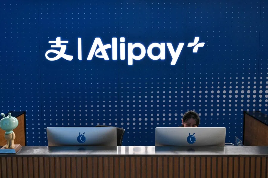 A receptionist works at her station at the headquarters of Chinese digital payments platform Alipay in the Pudong district in Shanghai on 12 November 2025. (Hector Retamal/AFP)