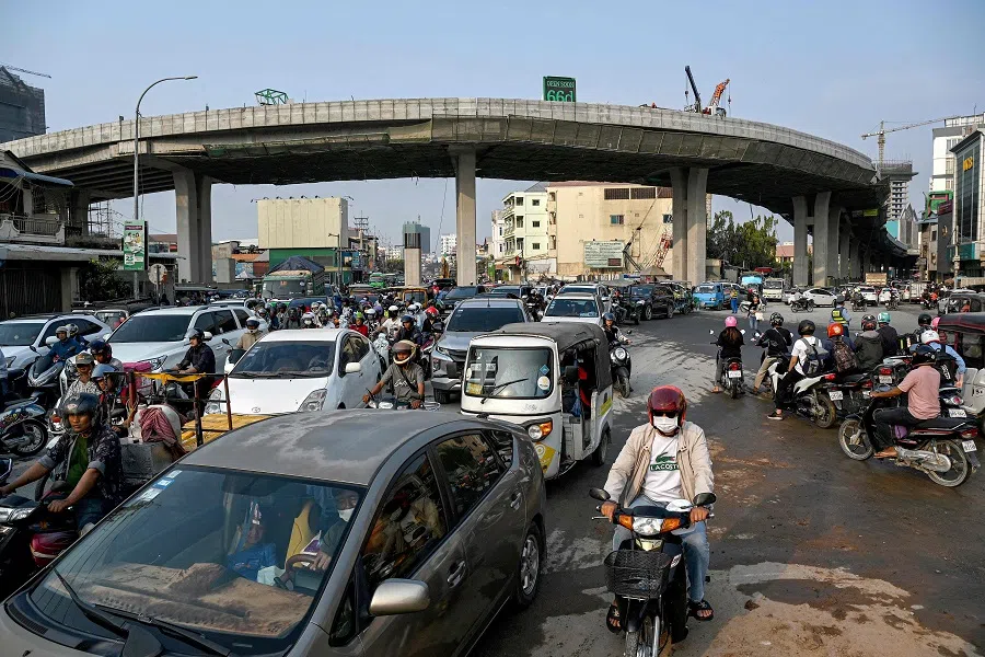 Motorists and cars make their way in traffic near an overpass under construction in Phnom Penh, Cambodia on 6 February 2024. (Tang Chhin Sothy/AFP)