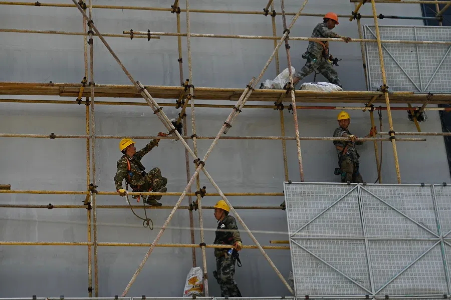 Men work on building of a store facade in Beijing, on 28 July 2024. (Pedro Pardo/AFP)