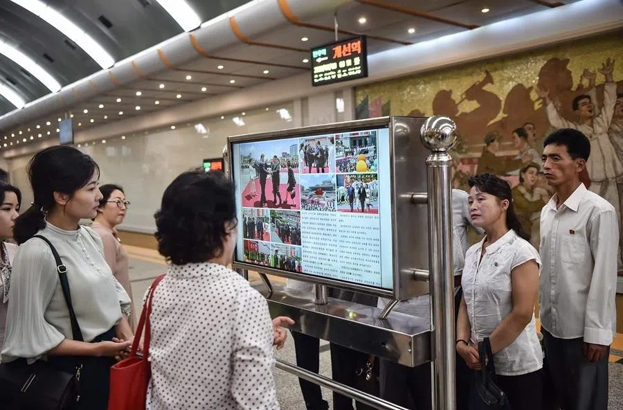 People look at a screen with the newspaper Rodong Sinmun showing the news on the visit of China's President Xi Jinping, in the Kaeson Station of the Pyongyang Metro in Pyongyang on 9 June 2026.