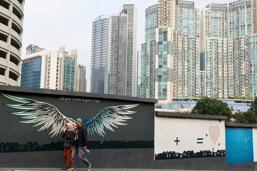 People walk beside a mural depicting wings with a background of office buildings and apartments in Jakarta, Indonesia, on 20 May 2024. (Ajeng Dinar Ulfiana/Reuters)