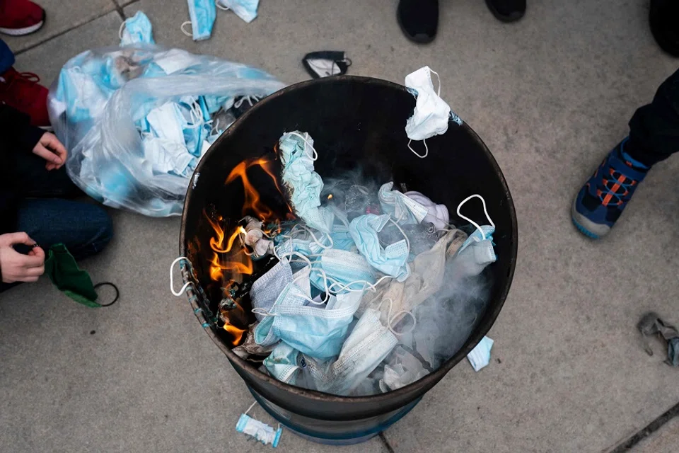 In this file photo taken on 6 March 2021, demonstrators throw masks into a fire during a mask burning event to protest Covid-19 restrictions, at the Idaho Statehouse in Boise, US. (Nathan Howard/Getty Images North America/AFP)