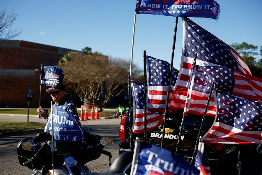 A supporter of Republican presidential candidate and former US President Donald Trump carries a flag in Conway, South Carolina, US, on 28 January 2024. (Randall Hill/Reuters)