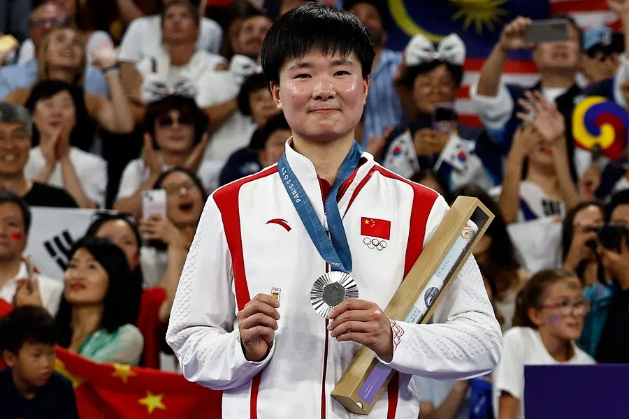 People’s Republic of China’s silver medallist He Bingjiao celebrates with her medal while holding a badge of the Spanish flag on the podium at the women’s singles badminton medal ceremony during the Paris 2024 Olympic Games at Porte de la Chapelle Arena in Paris, France, on 5 August 2024. (Luis Tato/AFP)