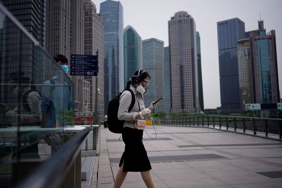 People wearing protective face masks walk past office buildings in Lujiazui financial district in Shanghai, China, on 4 June 2020. (Aly Song/Reuters)