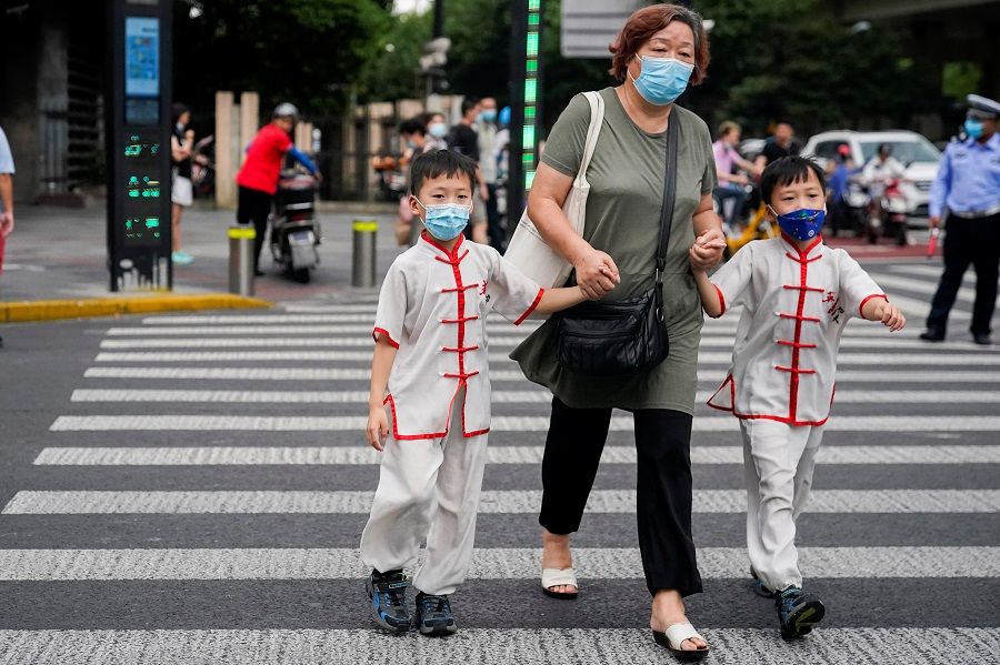 People wearing protective masks walk on a street in Shanghai, China, 10 August 2021. (Aly Song/Reuters)