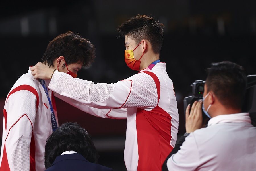 Silver medallist Liu Yuchen of China places the medal on teammate Li Junhui of China at the badminton men's doubles medal ceremony, Musashino Forest Sport Plaza, Tokyo, Japan, 31 July 2021. (Leonhard Foeger/Reuters)