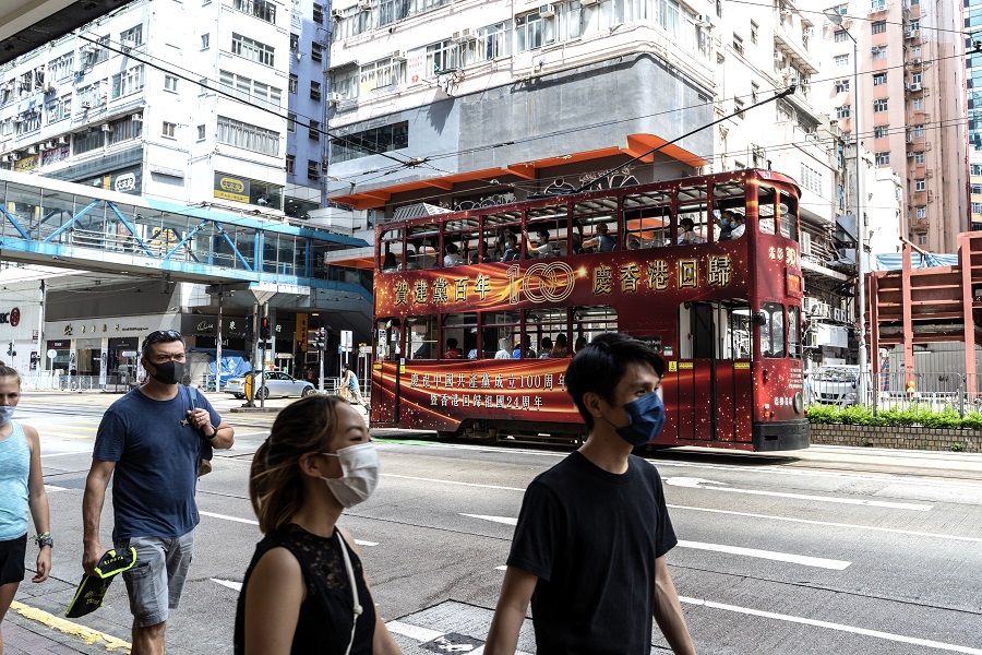 Pedestrians walk past a tram featuring an advertisement celebrating the centenary of the Chinese Community Party and the anniversary of Hong Kong's return to Chinese rule in Hong Kong, China on 1 July 2021. (Chan Long Hei/Bloomberg)