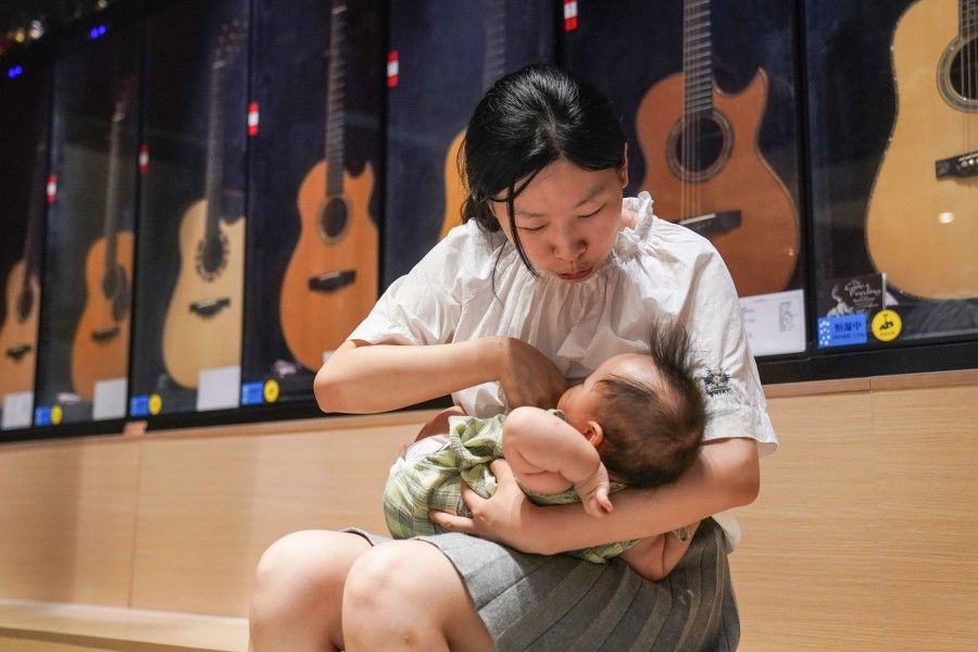 This photo taken on 5 August 2020 shows a mother feeding her child at her guitar store in Shanghai. Unregulated, aggressive promotion of formula milk, poor medical advice, short maternity leave and workplaces hostile to nursing mothers mean China has among the lowest breastfeeding rates in the world and is falling well short of its own targets, experts warn. (STR/AFP)