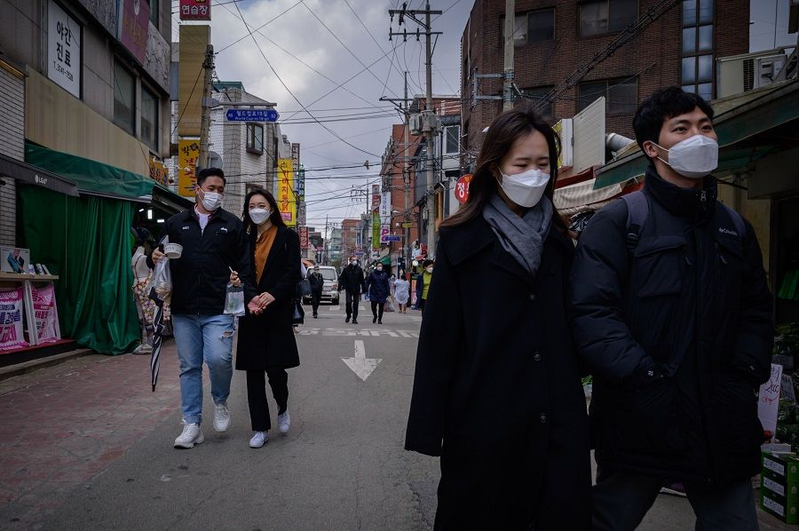 People wearing face masks amid concerns over the Covid-19 coronavirus walk through a market in Seoul on 22 April 2020. (Ed Jones/AFP)