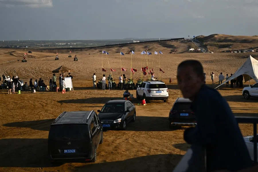 This picture taken on 10 August 2025 shows people visiting a tourist area in the Kubuqi desert near Ordos, in China’s northern Inner Mongolia region. (Pedro Pardo/AFP)