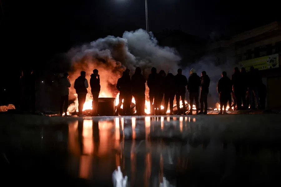 Protesters stand near burning tires in Ramallah in the occupied West Bank on 27 November 2023, ahead of an expected release of Palestinian prisoners in exchange for Israeli hostages held by Hamas. (Kenzo Tribouillard/AFP)