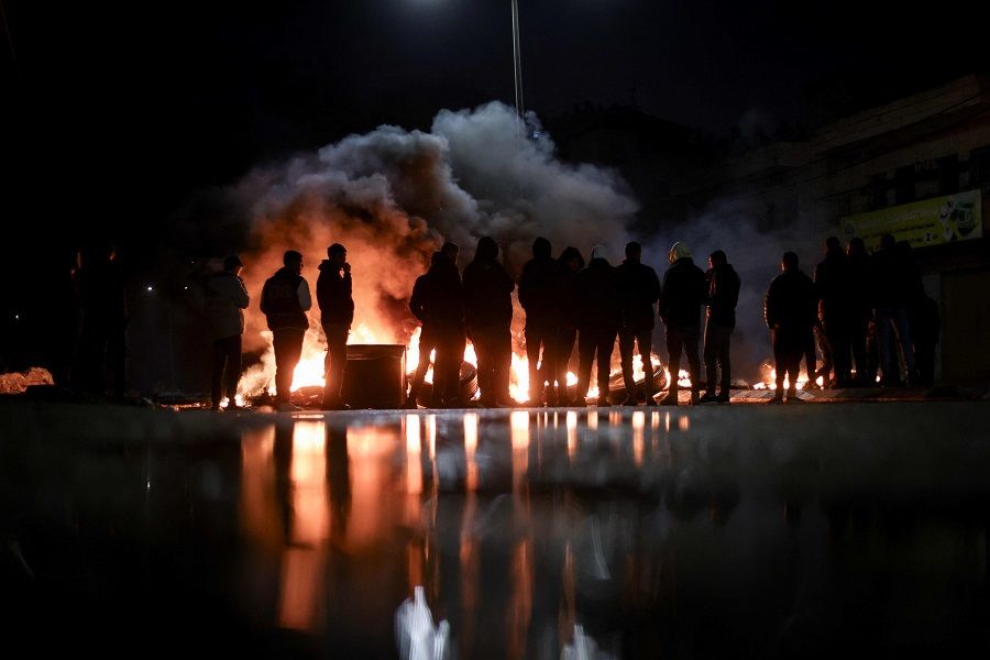 Protesters stand near burning tires in Ramallah in the occupied West Bank on 27 November 2023, ahead of an expected release of Palestinian prisoners in exchange for Israeli hostages held by Hamas. (Kenzo Tribouillard/AFP)